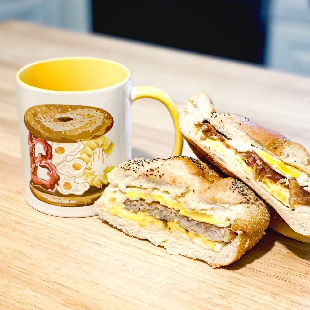 yellow bec bacon egg cheese mug two egg sandwiches light wood counter